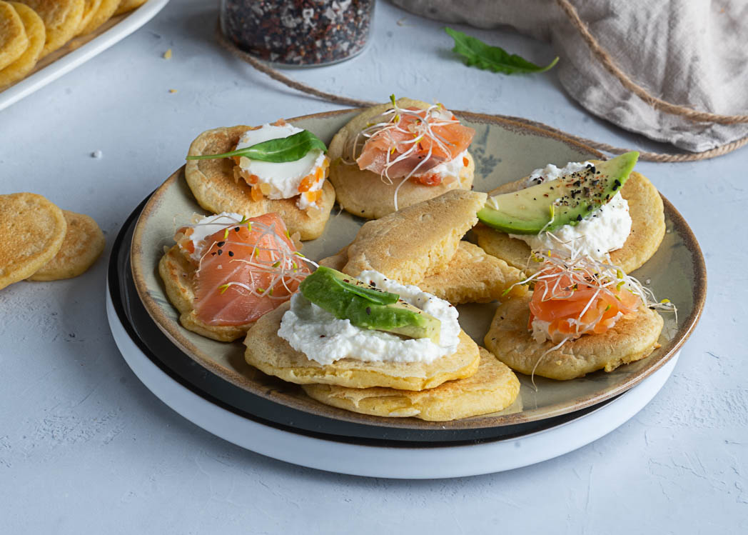 "Blinis salados esponjosos y dorados, apilados en un plato listo para servir