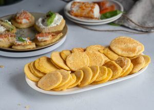 "Blinis salados rellenos de crema agria y salmón ahumado, servidos como aperitivo.